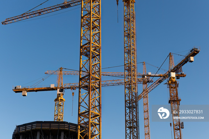 Close up of group of tower cranes against the blue sky in summer