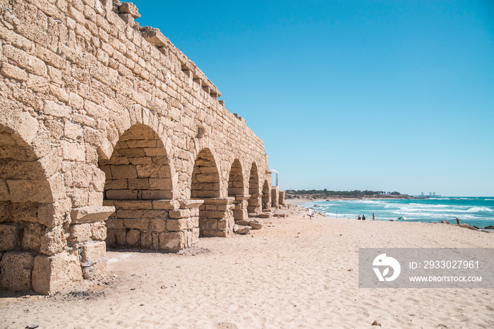 ancient roman aquaduct leading to bright blue ocean