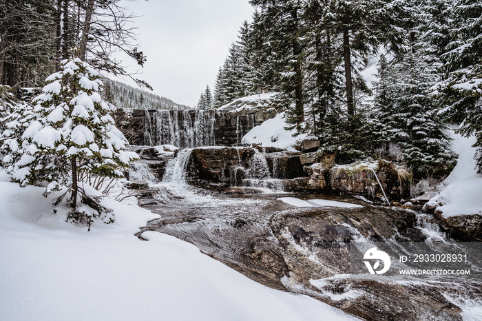 Winter waterfall called Certova strouha in Krkonose mountains,Czech Republic.Snowy frozen landscape.Frozen waterfall and wild stream,long exposure water.Czech National Park.Winter forest creek