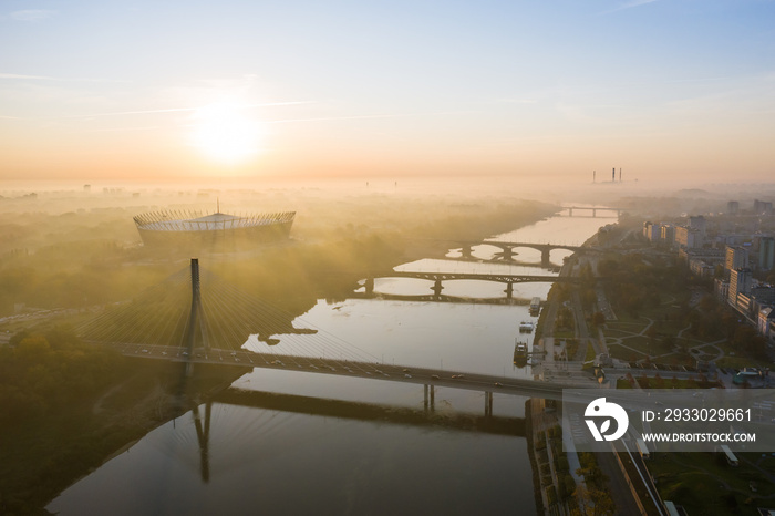 Drone landscape shot in the city of Warsaw, Poland. Aerial view of the Warsaw sky, river, bridge and roadway at sunrise on a foggy morning.