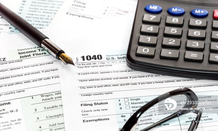 Pen, glasses and calculator on tax form 1040. business concept.