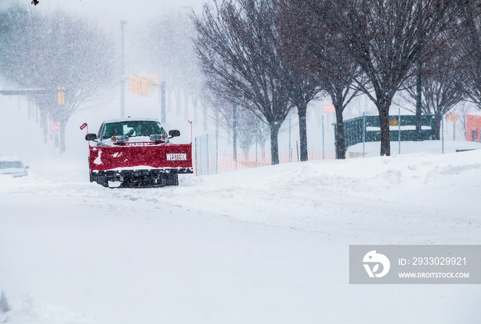 red snow plow truck clearing snow covered road in Baltimore city, Maryland