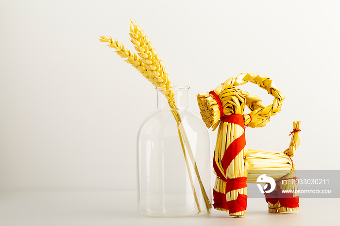 horse made of straw, a symbol of Maslenitsa and Easter, with a transparent jug with wheat stalks on a light background