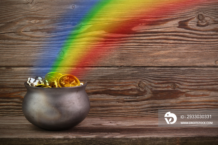 Rainbow pot of gold on old wooden background. St. Patrick’s day symbol