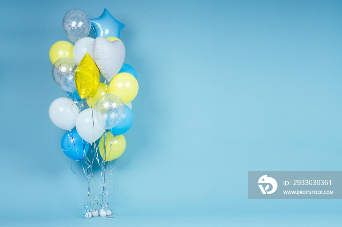 yellow, blue and white balloons on blue wall background copy space. Colorful balloon in room prepared for birthday party. copyspace helium balloons