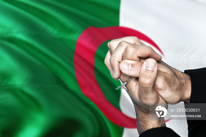 Algeria flag and praying patriot man with crossed hands. Holding cross, hoping and wishing.