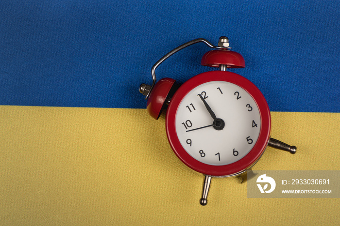 Ukrainian flag and vintage alarm clock, close up. Time to learn Ukrainian. Time to travel around Ukraine