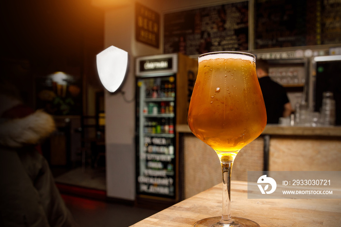 Light beer in a glass, interior pub on the background.