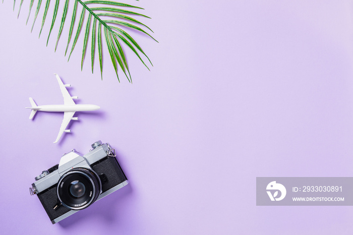 Top view flat lay mockup of retro camera films, airplane, leaves and traveler accessories isolated on a purple background with copy space, Business trip, and vacation summer travel concept