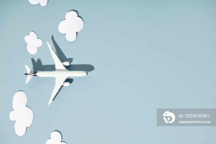 Miniature toy airplane and paper clouds on colorful background. Flat lay design of travel concept