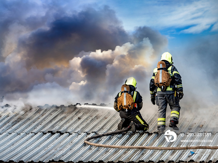 Emergency. Firefighters extinguish the flame on the roof of the building. Roofing houses covered fire. Rescuers pour fire. Firefighters in uniform. Fire on the roof of the house.