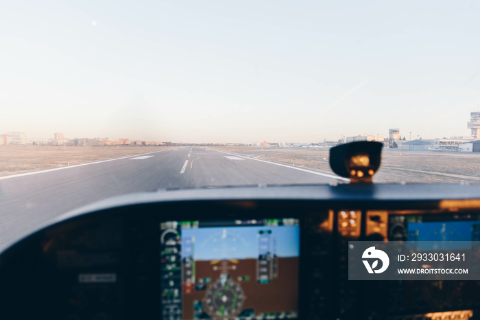 Cockpit of a small plane landing on the airport runway at sunset