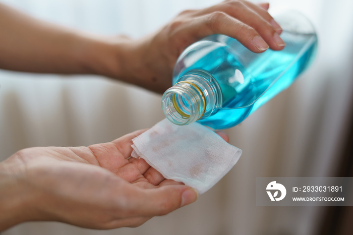 Pouring ethyl alcohol from bottle  into a cotton piece for corona virus or Covid-19 protection.