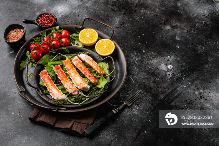 Snow crab legs with fresh lemon slices and butter sauce, on black dark stone table background, with copy space for text