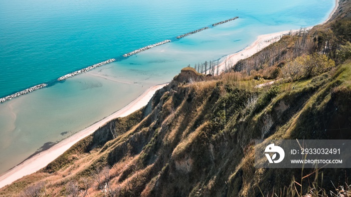 Panoramic view of cliffs of the rugged coastline with breakwaters protecting the beach of Fiorenzuola di Focara (Pesaro, Marche, Italy)