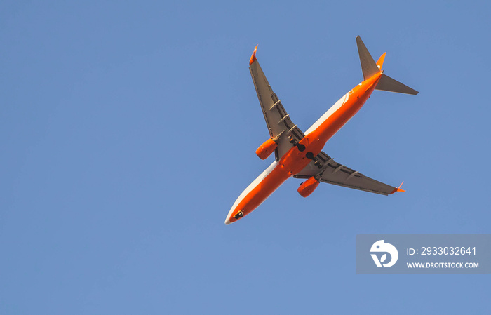 red passenger plane close-up flying in the sky