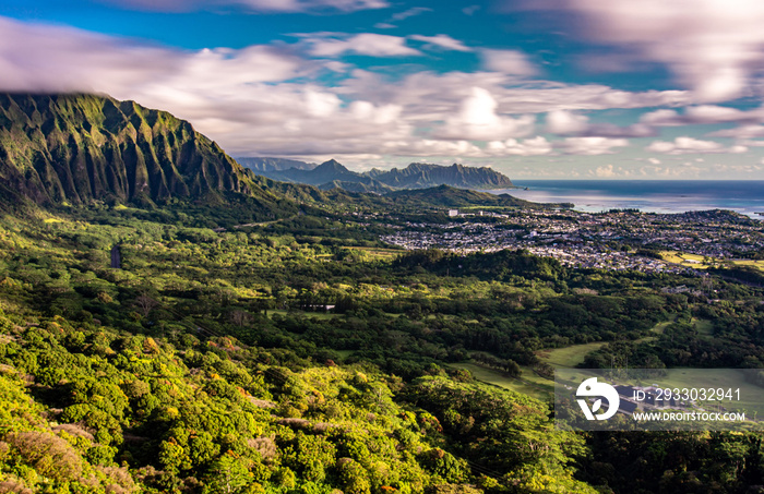 Panoramic aerial image from the Pali Lookout on the island of Oahu in Hawaii. With a bright green rainforest, vertical cliffs and vivid blue skies.