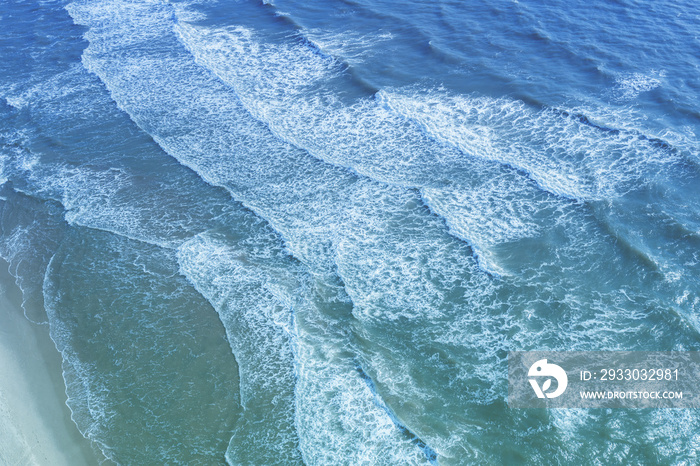 Seascape. Sandy beach. Sea waves roll onto the sandy beach. Top diagonal view. Abstract nature landscape background