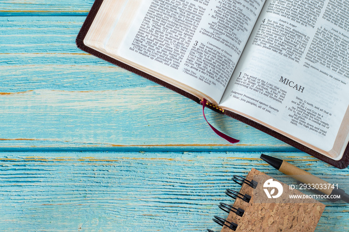 Micah open Holy Bible Book on a rustic wooden table background with a notebook and pen. Copy space. Studying old Testament prophecy, Christian biblical concept. Top view. Flat lay.