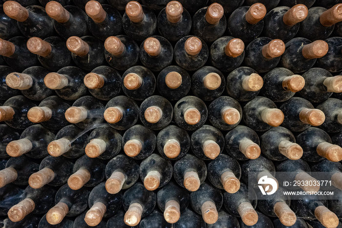 Wine bottles stacked up in old wine cellar close-up background