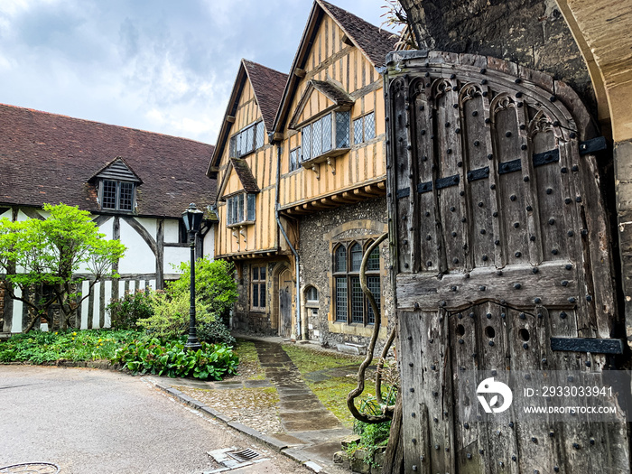 Cheney Court and old medieval stables view in Winchester. Half timbered tudor architecture. Yellow half timbered tudor house near Cathedral in Winchester. Stables. Through the gate. Hampshire, England