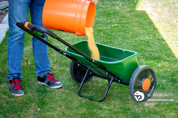 Man pours fertilizer into a drop spreader