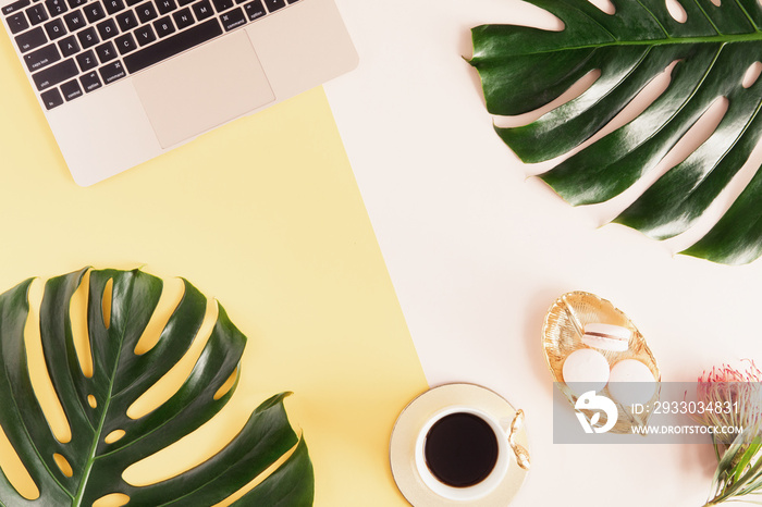 Flat lay and top view of woman desk with laptop, decorated with palm leaf. Feminine work space, freelancer desk at summer time. Flatlay