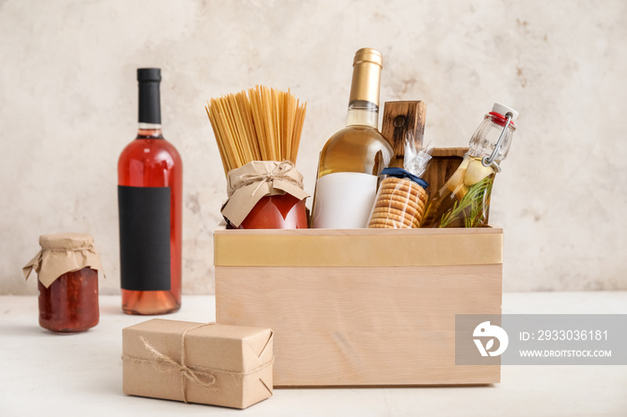 Gift basket with products and present on light background