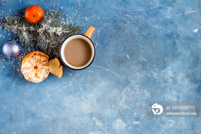 New Year’s composition. Cup of coffee with milk, tangerines, fir branches and Christmas decorations on a blue textured background. Christmas, winter, new year concept. Flat lay, top view.