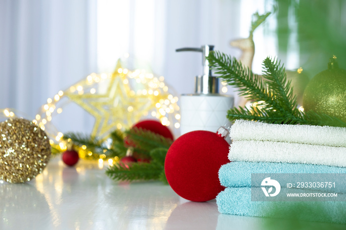 Stack of blue and white towels folded on the table, fir branches, Christmas balls and Christmas lights. SPA massage or beauty salon, skin care and body care in Christmas or New Year variant.