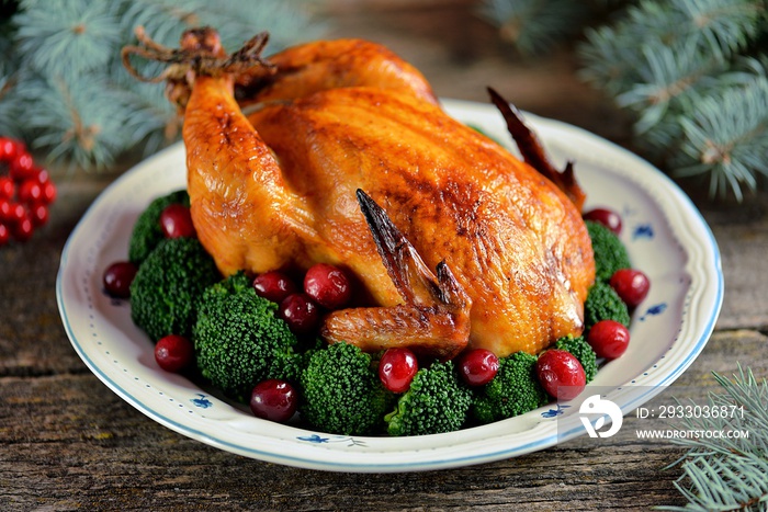 Grilled chicken with boiled broccoli and cranberries on a wooden background. Christmas background.