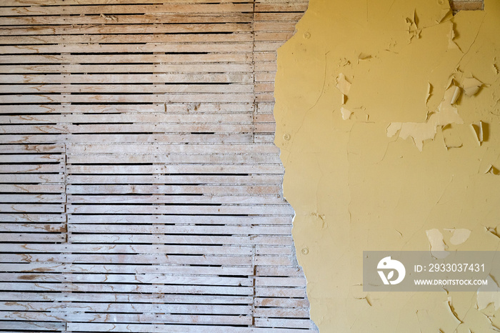 Exposed beams, framing and studs with peeling yellow paint on the wall. Useful for abstract backgrounds