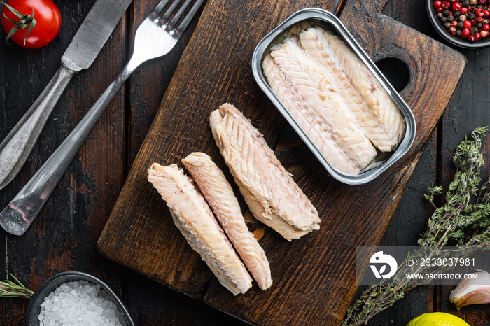 Canned Mackerel  fillet, fish preserves, on wooden cutting board, on old dark  wooden table background. with herbs and ingredients, top view flat lay