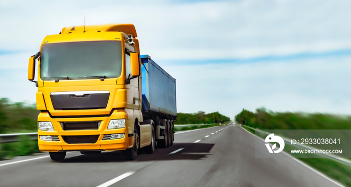 Yellow truck with blue semi-trailer rushes to left on highway. Copy space. Delivery banner.