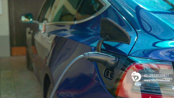 CLOSE UP: Charger is plugged into a modern electric car with an empty battery.