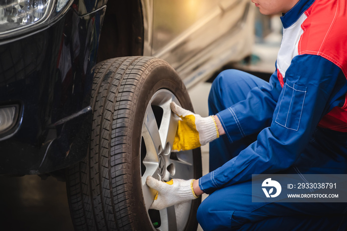 Asian car mechanic is removing the wheel and checking the brakes and suspension in the car service with a forklift. Repair and maintenance center