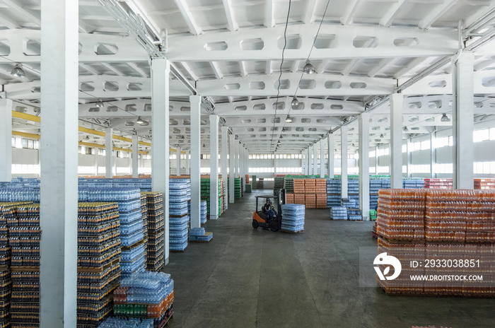 panoramic view of a large warehouse with drinks in plastic bottles with loading machines