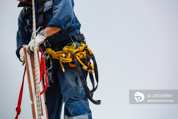 Closeup male worker standing on tank male worker height roof tank knot carabiner rope.