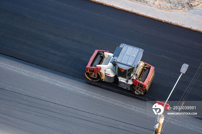 Asphalt road roller with heavy vibration roller compactor press new hot asphalt on the roadway on a road construction site. Heavy Vibration roller at asphalt pavement working. Repairing.