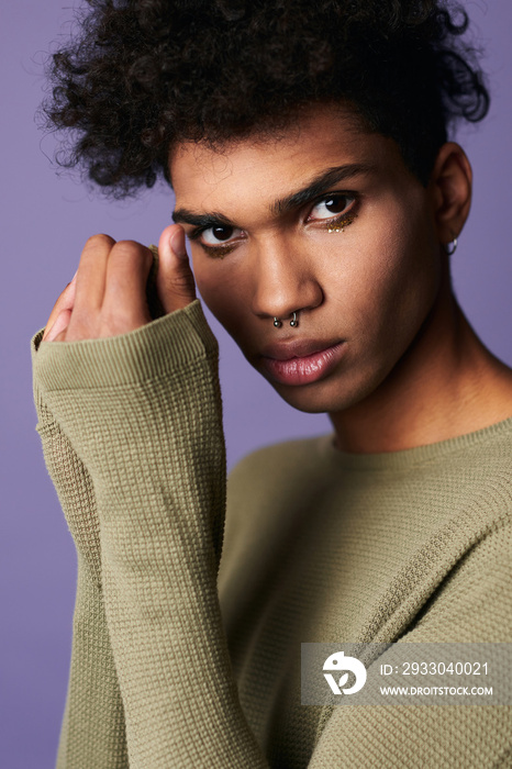 Transgender latino young man looking camera on purple background. Close up verticale portrait