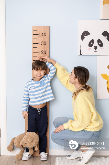 Woman measuring height of her little son at home