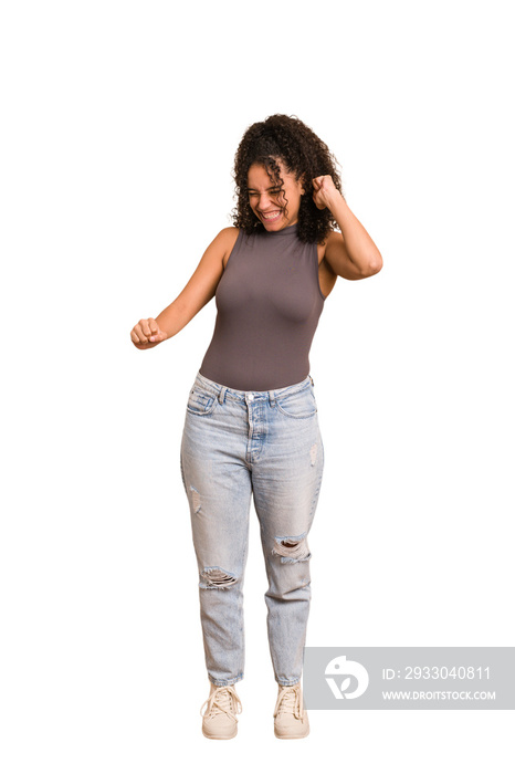 Young african american woman with curly hair cut out isolated dancing and having fun.