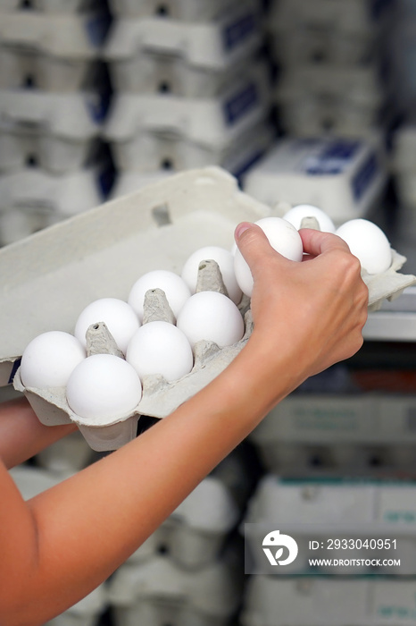 Hands woman with packages of white eggs in the store or supermarket. Woman buys eggs. Buying eggs at the grocery store