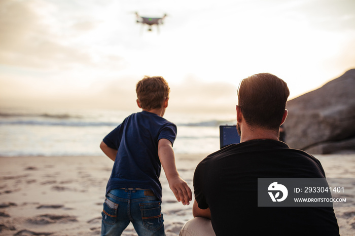 Father and son on the beach flying drone