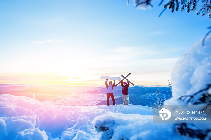 Two active friends snowboarder and skier standing on mountain top blue sky sunrise. Concept ski resort winter forest