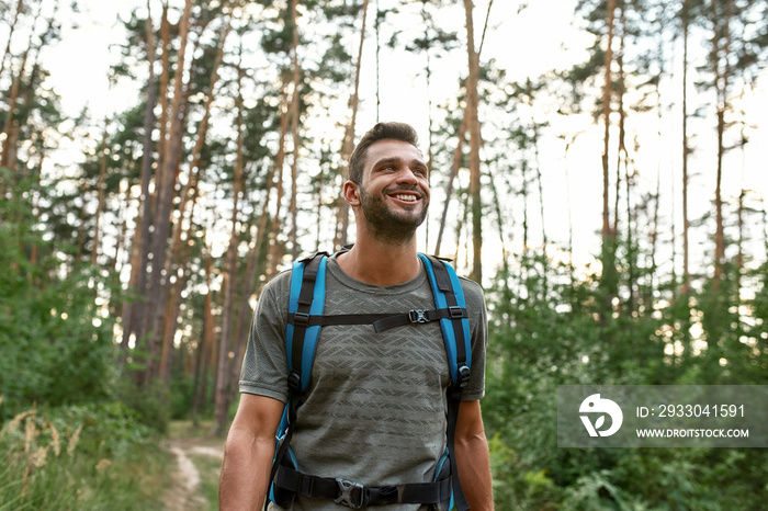 Portrait of smiling young caucasian man trekking in forest