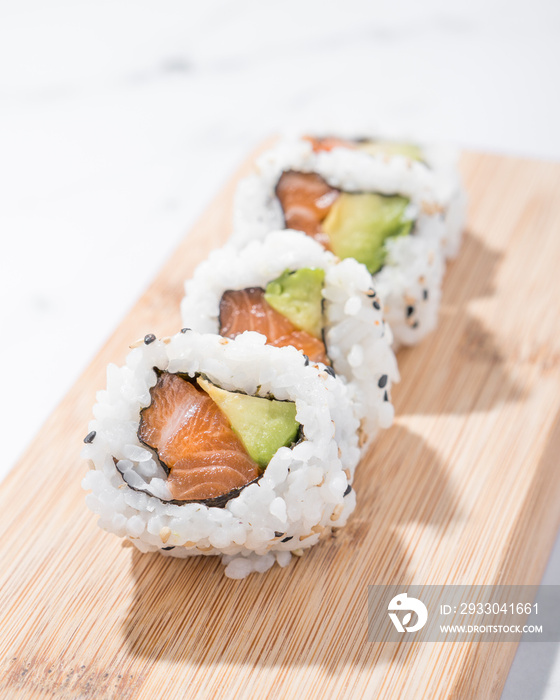 Salmon and avocado sushi pieces on a wooden table