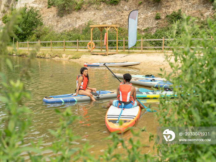 Friends relaxing on paddleboard on lake