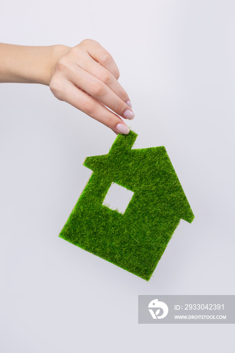 Female hands hold a model of a green house close-up. Sale of ecological real estate of the future.