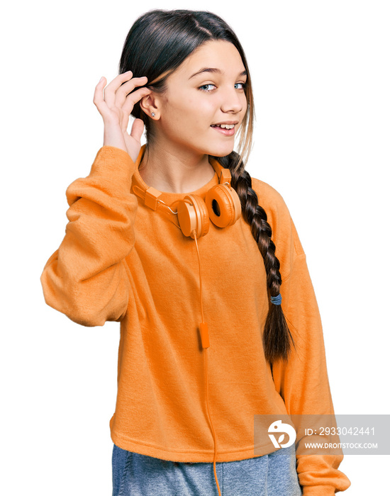 Young brunette girl with long hair wearing sweatshirt and headphones smiling with hand over ear listening an hearing to rumor or gossip. deafness concept.